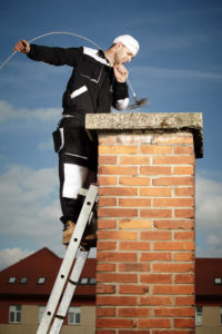 chimney sweep at the top of chimney with brush