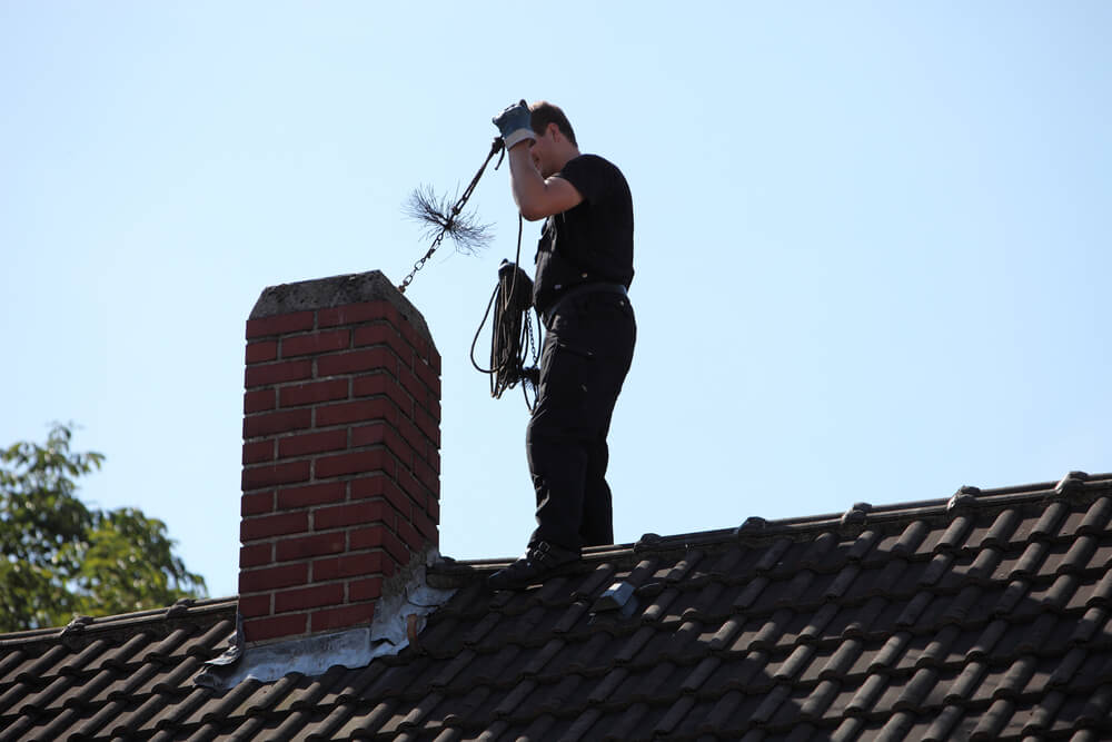 chimney sweep on roof inspecting chmney