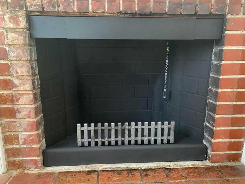 New Ahren Fireplace with damper chain and grate with a brick surround.