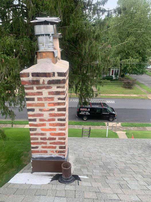 Chimney has 3 levels of inspections.  Tall Chimney with new tuckpointing and crown with work van on the street.