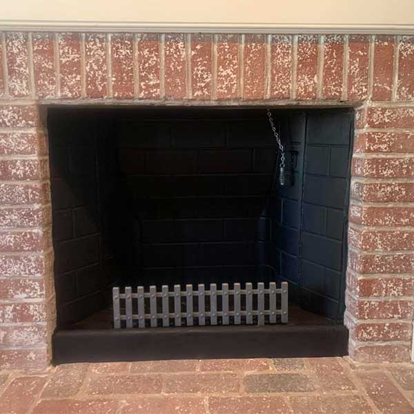 Fireplace with brick surround, damper chain and grate.