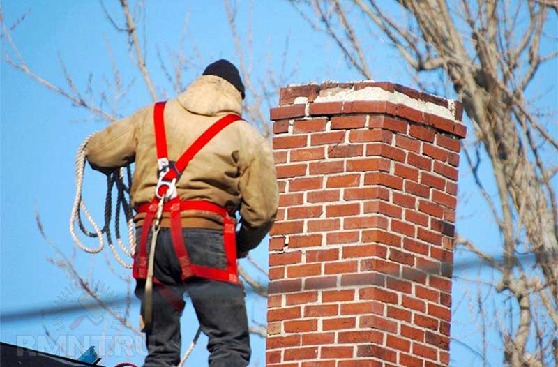 Chimney Repair Services - tech on roof beside chimney wearing safety equipment.